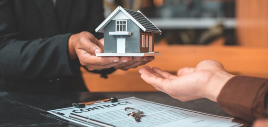 A hand passing a model of house to another hand