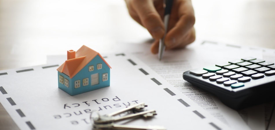 A model of house, a calculator and a pencil on top of tax papers