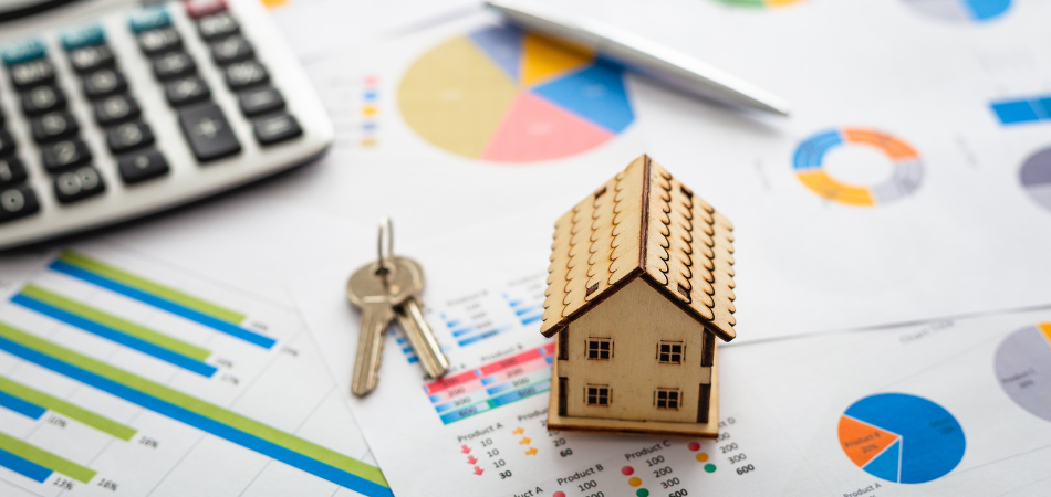 Model house, keys, calcuator and a pen on top of papers