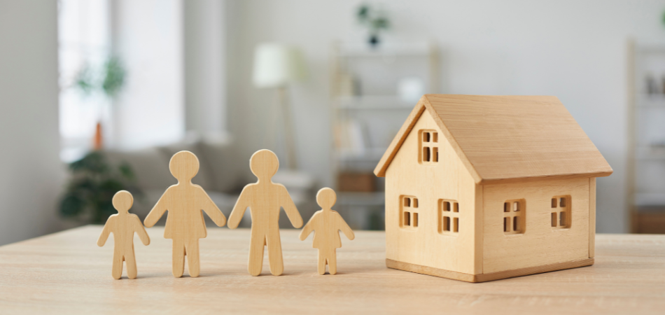 A model house next to a model family made of wood 